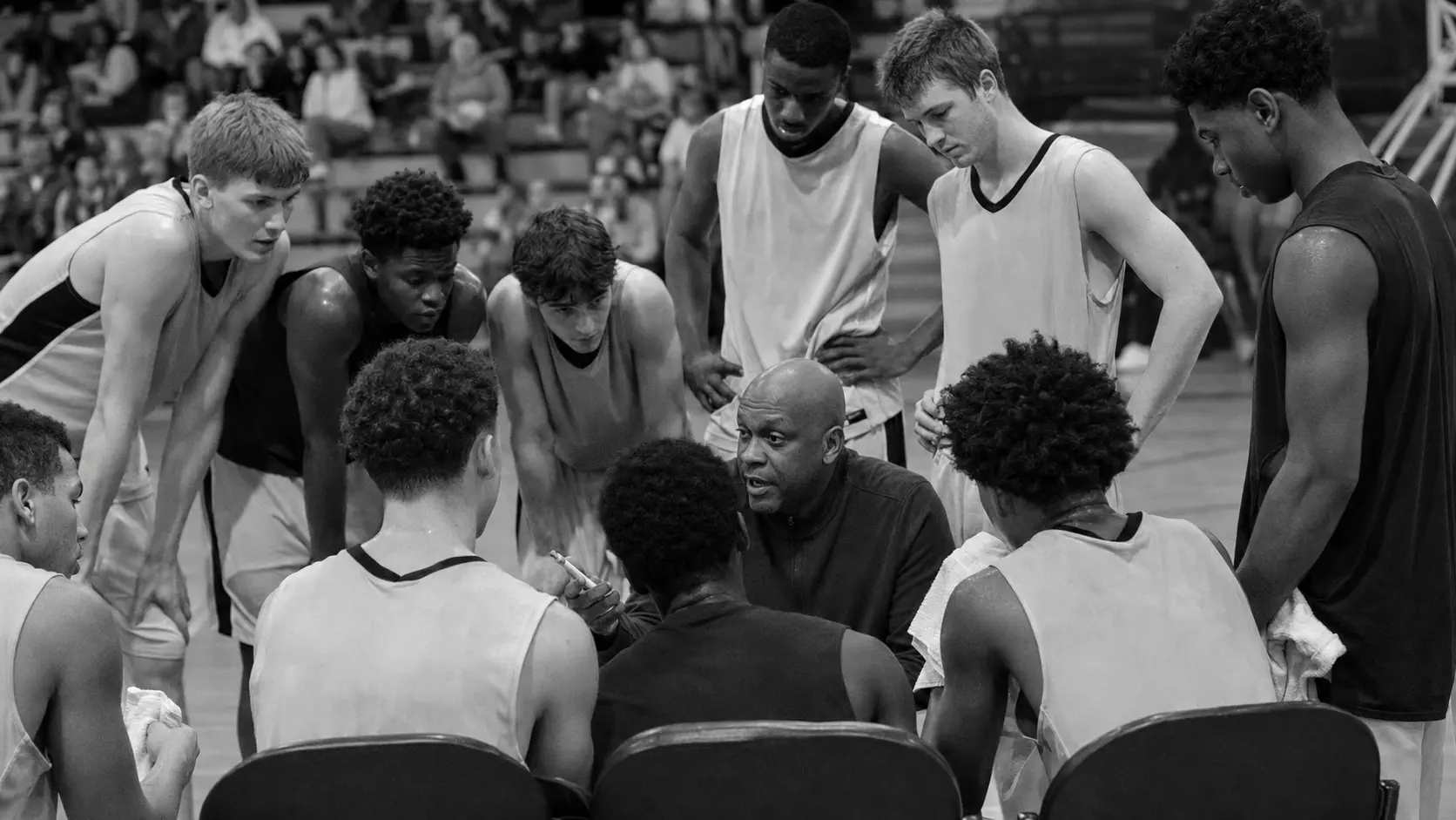 Diverse male basketball team listening to their coach during a timeout huddle
